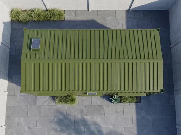Design visualisation of the olive-green porta cabin from directly above, showing its ribbed, gently pitched roof with a small roof light and planters along one long side, on a paved yard between concrete walls