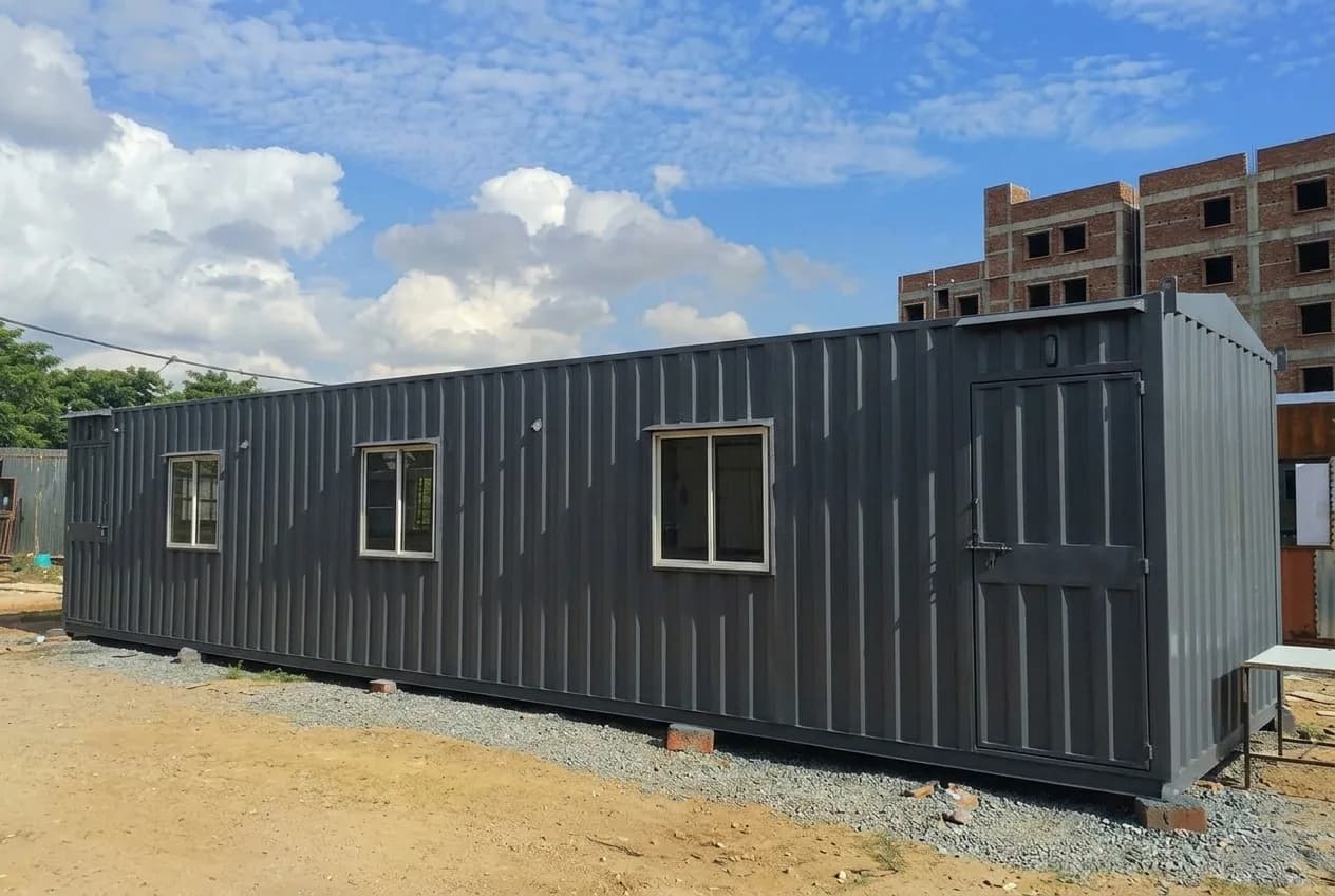40 × 10 ft portable site office — a long charcoal-grey unit with three sliding windows and an end door at a construction site, by Porta Cabin Systems