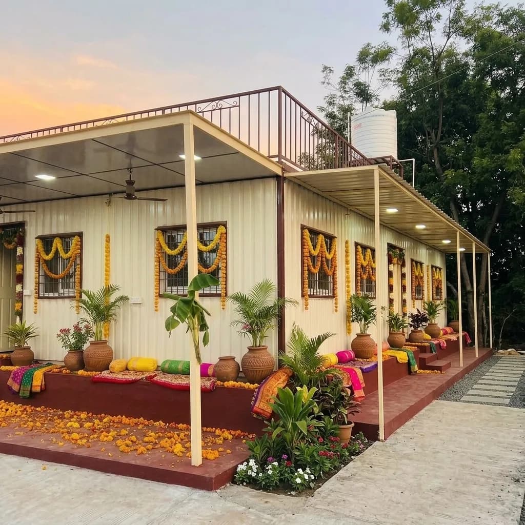 Cream portable farmhouse cabin with a covered verandah and rooftop terrace, dressed with marigold garlands, by Porta Cabin Systems