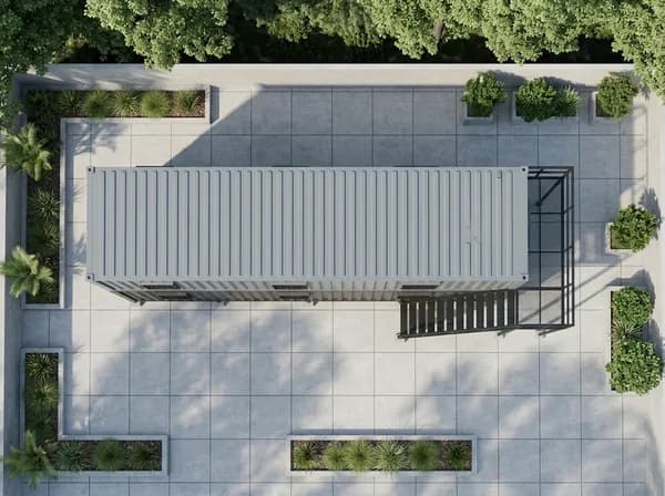 Design visualisation of a two-storey porta cabin seen from directly above, showing the long grey corrugated top of the upper cabin with the staircase and its landing at one end, on a paved yard edged with planting beds